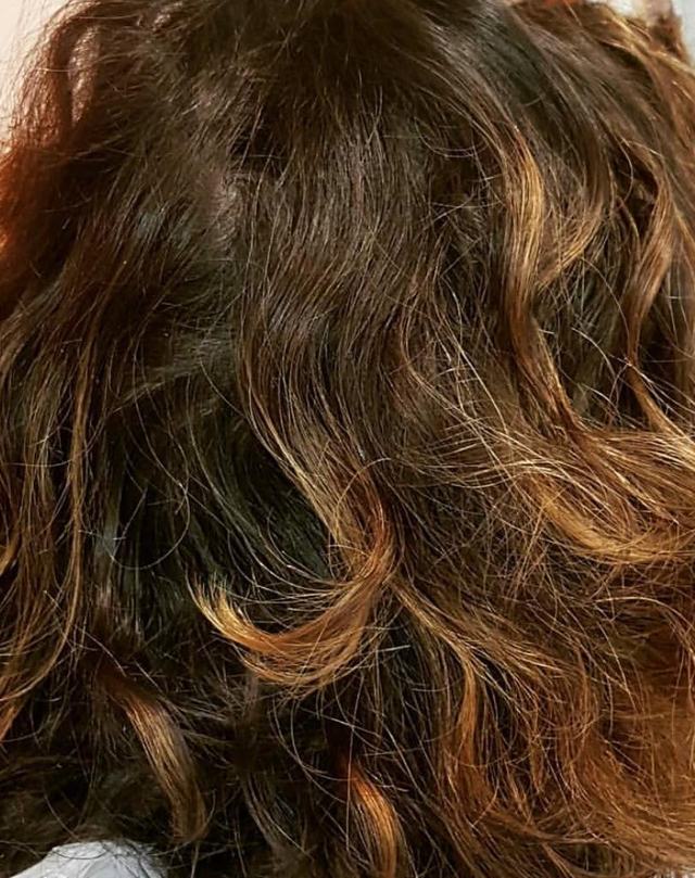 Avant : cheveux mi-longs ondulés et non coiffés, base brune à reflets caramel