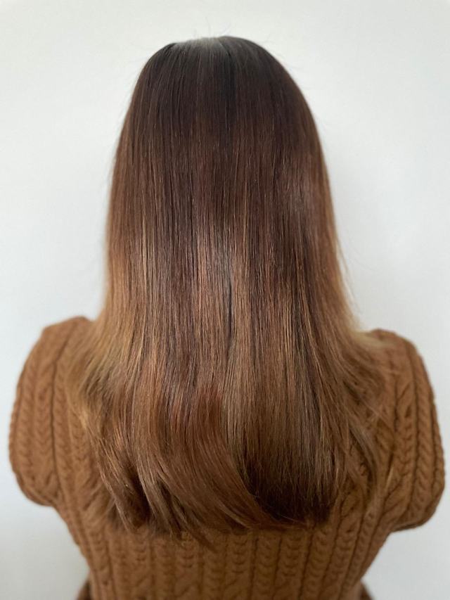 Balayage caramel cuivré sur cheveux longs lisses, racines châtain foncé